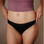 Frontalansicht einer Frau mit dem Everyday DORIS Slip Strong aus feiner Eyelash Lace Spitze. Die edle italienische Spitze zeigt ein zartes, florales Muster und verleiht dem Slip eine elegante, feminine Ausstrahlung. Die leicht erhöhte Leibhöhe formt eine natürliche Silhouette, während der weiche Frottee-Zwickel den ganzen Tag über Komfort bietet. Nachhaltig gefertigt in Portugal aus recycelter Spitze, vegan und hautfreundlich.