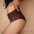 Frau in High-Waist-Periodenunterwäsche chocolate leo im Profil, nahtfreie Verarbeitung an Bauch und Beinen, flexible Passform und auslaufsichere Smart-Layer-Technologie bei starker Blutung.