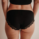 Detailaufnahme der Rückseite der Hipster-Periodenunterwäsche. Die Panty schmiegt sich eng an und bietet dank der Smart Layer Technologie maximale Sicherheit ohne Auslaufen. Der Stoff bleibt auch bei Bewegung an Ort und Stelle und verhindert ein unangenehmes Windelgefühl. Die nachhaltige Spitze aus Italien rundet das hochwertige Design ab.